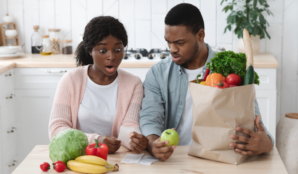 Couple In Kitchen Checking Bill After Grocery Shopping