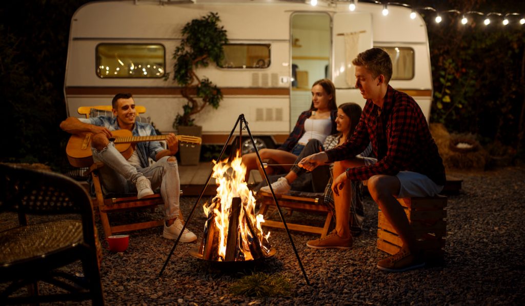 Friends playing on guitar by the campfire, camping