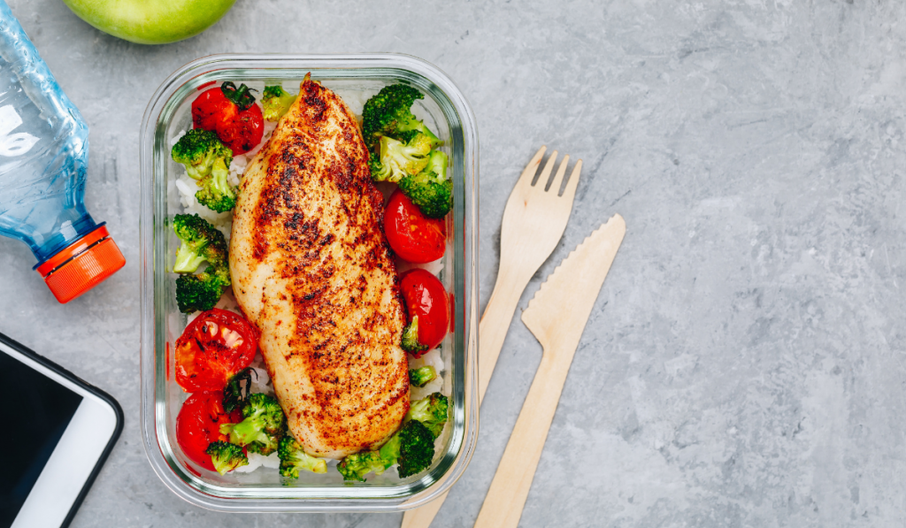 Grilled chicken meal prep containers with rice, broccoli and tomatoes.