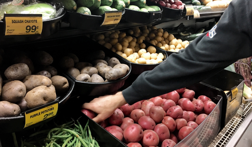 man picking potatoes at the grocery store
