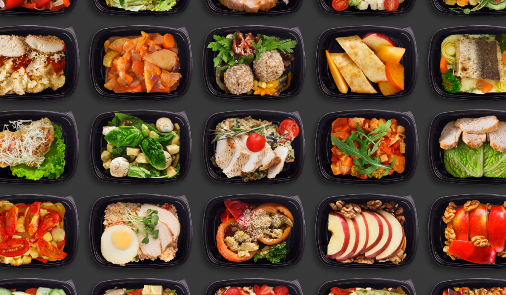 Healthy Nutrition Delivery. Tasty Everyday Meals In Lunch Boxes Over Black Background