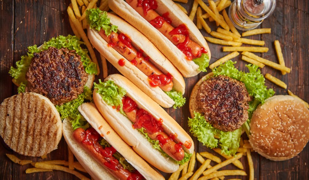 Hot dogs, hamburgers and french fries on wooden table