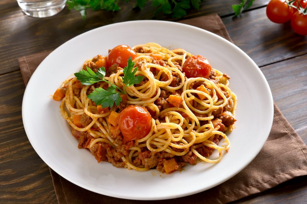 Spaghetti bolognese on white plate and wooden table
