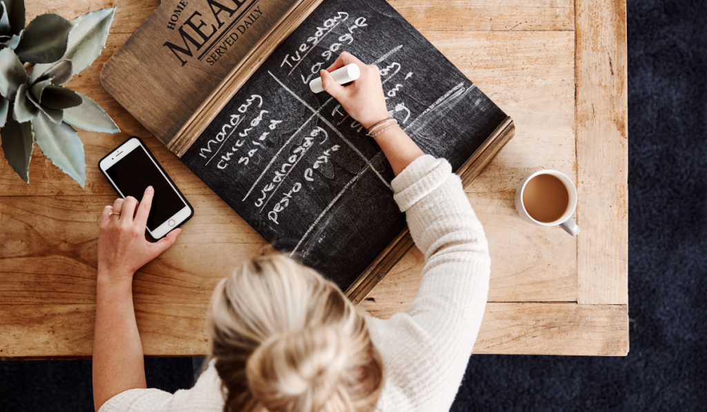 woman writing her meal plan on chalk board