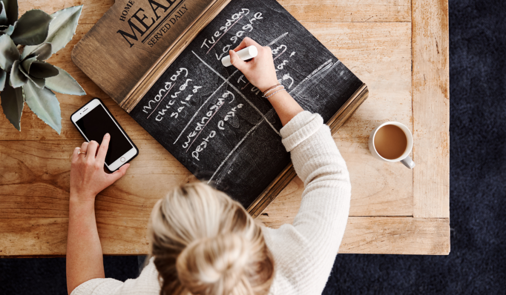 female writing meal plan on a chalk board