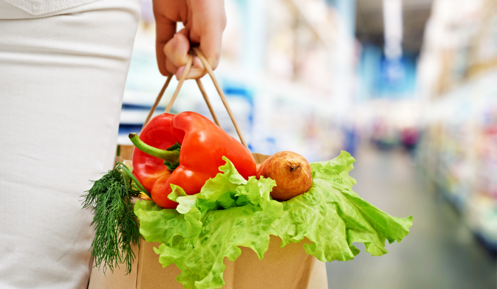 a woman holding a bag of fruit and vegetables

