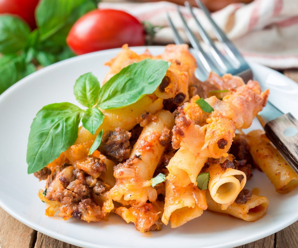 baked ziti bolognese on white plate pasta with meat tomate sauce and cheese 