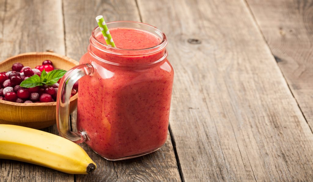 banana and cranberry smoothie in a jar on the table 