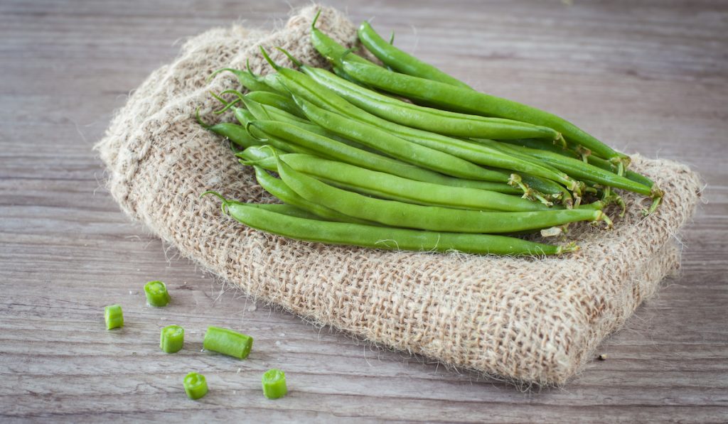 green beans placed on cloth and pieces of sliced green beans on table