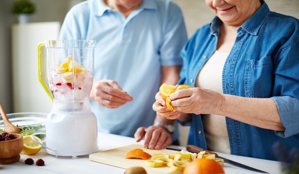 senior couple making smoothie using a blender 