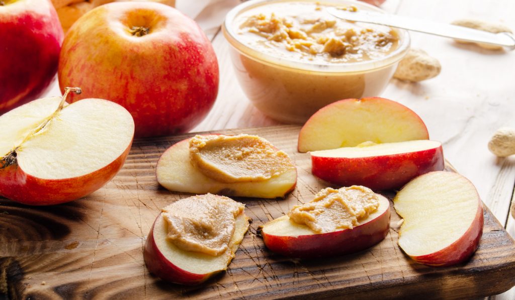 sliced apples with peanut butter spread on it perfect for toddler snack
