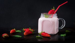 strawberry yogurt with milk with fresh strawberries on the black background