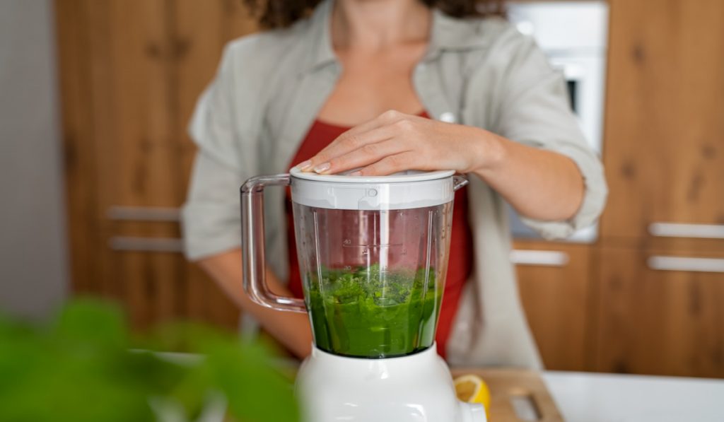 woman making healthy smoothie in a blender